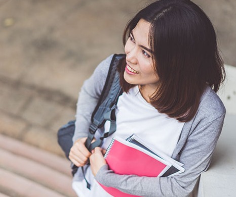 Image of a person standing on stairs holding text books
